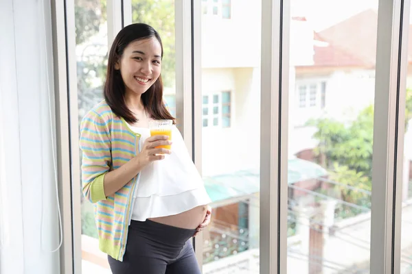 Junge gesunde asiatische Schwangere lächeln, während sie ein Glas Wasser in der Hand halten (Gesundheitskonzept)) — Stockfoto