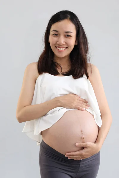 Volle Länge junge asiatische Schwangerschaftsbauch in weißem Kleid mit glücklich lächelndem Gesicht Porträt und steht auf weißem Hintergrund — Stockfoto