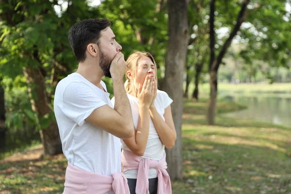 Giovani caucasici coppia persone che indossano tuta sportiva sono innamorati. sbadigliare mentre l'esercizio nel parco in estate con alberi verdi natura — Foto Stock