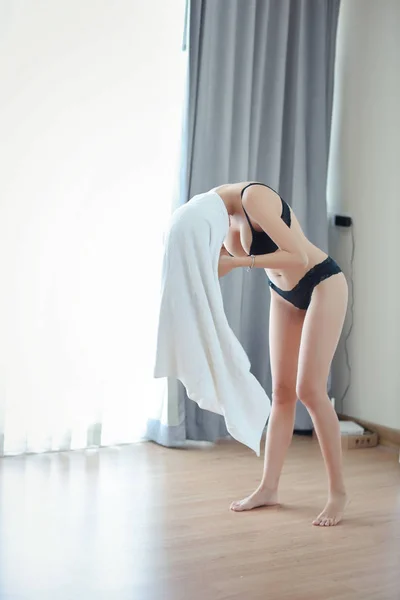 Longitud completa impresionante disparo de hermosa mujer asiática que en toalla blanca y lencería negro mientras está de pie en el dormitorio, preparándose para la ducha —  Fotos de Stock