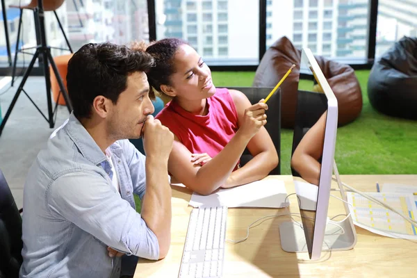 close up of caucasian graphic design and coworker in smart casual wear talking and working on computer in creative office with happy and smiling face