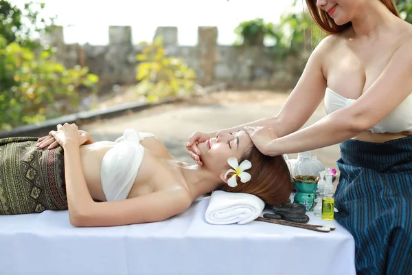 Face massage, two beautiful and sexy asian young women in white dress enjoying oil spa massage salon during sunny day with happy face