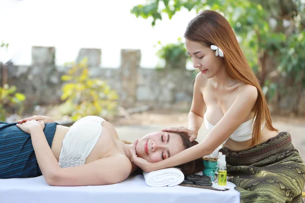 Массаж лица, две красивые и сексуальные азиатские девушки в белом платье, наслаждающиеся массажным салоном масляного массажа в солнечный день со счастливым лицом — стоковое фото