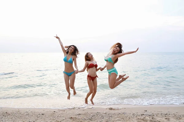 Teli szemcsésedik-ból fiatal ázsiai gyönyörű és örömteli lányok a bikini, aki jumping, és felhívja a kezét a trópusi tengerpart, boldog és mosolygott nyaralni nyaralás kék ég (párt és barátság koncepció) — Stock Fotó