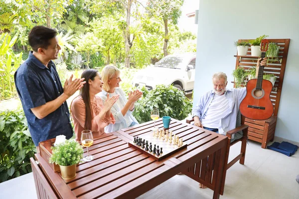 high angle view of a group of multiethnic senior people playing guitar and sing a song after playing chess board with happy smiling face on sunny day