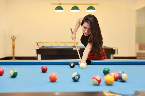 Young beautiful asian woman playing and aiming for billiards ball on blue pool table in club — Stock Photo, Image