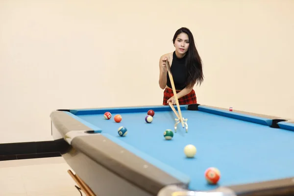 Bella e sexy donna asiatica in abito nero giocare a biliardo o snooker sul tavolo da biliardo blu con felice volto sorridente durante le vacanze — Foto Stock