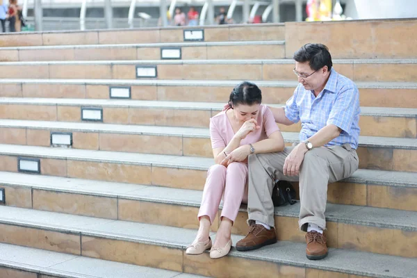 Ältere asiatische Ehemann tröstet ältere asiatische Frau und legte seine Hände auf ihre Schulter mit Liebe, weil sie ihre Handtasche gestohlen wurde, während sie in der Innenstadt saß — Stockfoto