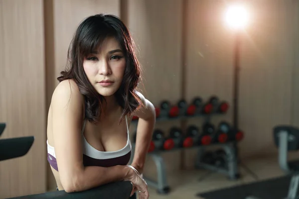 Porträtt av ung frisk och sportig asiatisk kvinna som tar en paus efter träning i gym (denna bild för fitness och träning koncept) — Stockfoto