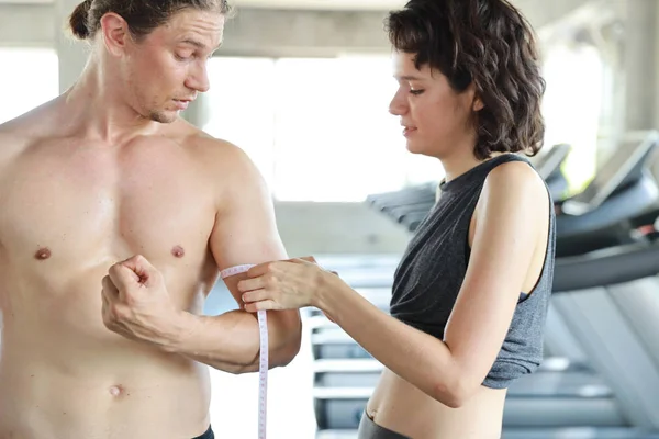 Pár zdravý běloch pomocí měřicí pásky se svým přítelem biceps — Stock fotografie