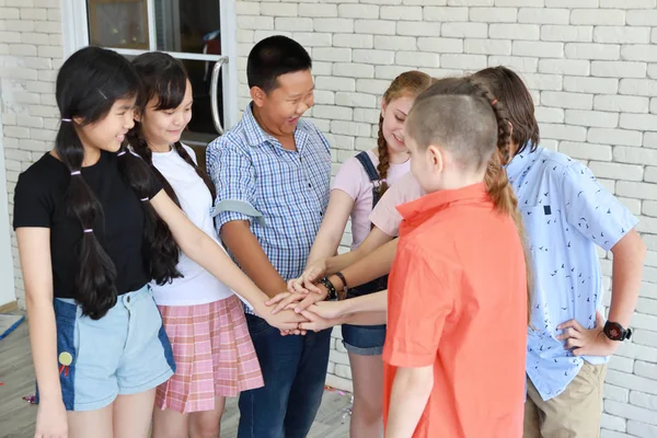 Grupo de crianças da escola empilhando as mãos em sala de aula (educação conc — Fotografia de Stock