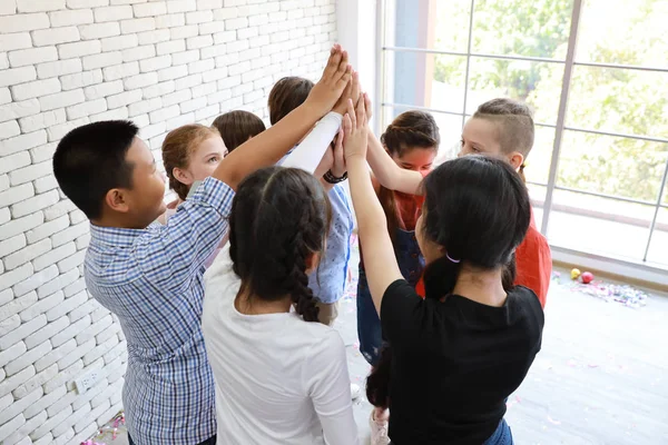 Skupina školáků skládající ruce ve třídě (vzdělávání conc — Stock fotografie