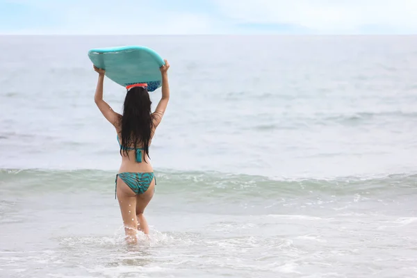 Visão traseira sexy surfista asiática menina segurando prancha verde no mar tropical em traje de banho verde na praia de areia no verão. (Desporto aquático ou férias conceito de férias) — Fotografia de Stock