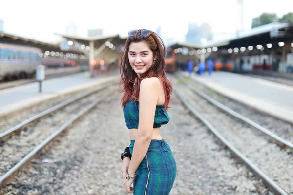 若いですアジアの女性の肖像で緑のドレスとともに太陽の輝き立ち位置とポーズで電車の駅に笑顔と美しさの顔 — ストック写真