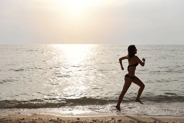 Felicidad en vacaciones silueta lado ver imagen de joven asiático hermosa y sexy chica en bikini negro que se ejecuta en la playa de arena en la puesta de sol en las vacaciones de verano — Foto de Stock