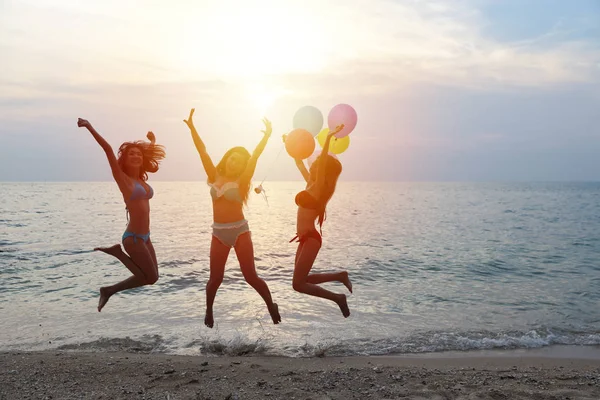 Teljes lövés a fiatal ázsiai gyönyörű és vidám lányok bikini, aki ugrás és felemeli a kezét, miközben tartja léggömbök trópusi strandon boldog mosolygós arcok nyaralás — Stock Fotó