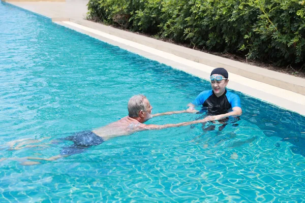 Feliz anciano caucásico marido y anciano asiático esposa nadando en piscina durante las vacaciones de jubilación con relajación en día soleado —  Fotos de Stock