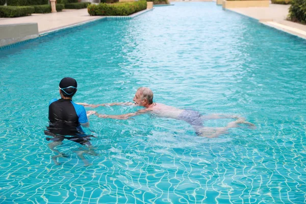 Feliz anciano caucásico marido y anciano asiático esposa nadando en piscina durante las vacaciones de jubilación con relajación en día soleado —  Fotos de Stock