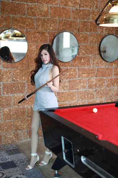 Completo comprimento jovem bela mulher asiática jogar bilhar bola no vermelho piscina mesa no clube e olhando para câmera — Fotografia de Stock
