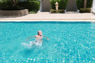 Mutlu beyaz tenliler emeklilik tatilinde havuzda yüzmeyi rahatlama ve gülümsemeyle öğrenirler.
