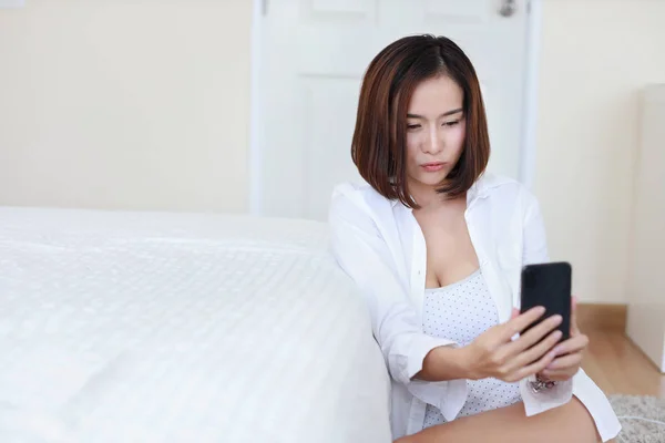 Giovane attraente asiatico donna indossare bianco camicia utilizzando VDO chiamata da cellulare e dare bacio in bianco camera da letto — Foto Stock