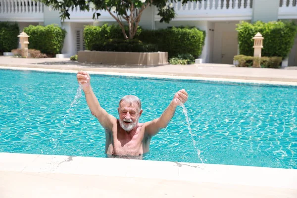 Feliz anciano caucásico aprender a nadar en la piscina durante las vacaciones de jubilación con la relajación y sonriendo — Foto de Stock