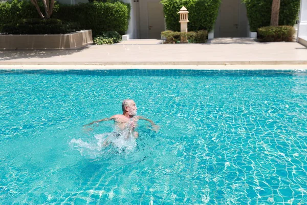 Feliz anciano caucásico aprender a nadar en la piscina durante las vacaciones de jubilación con la relajación y sonriendo — Foto de Stock