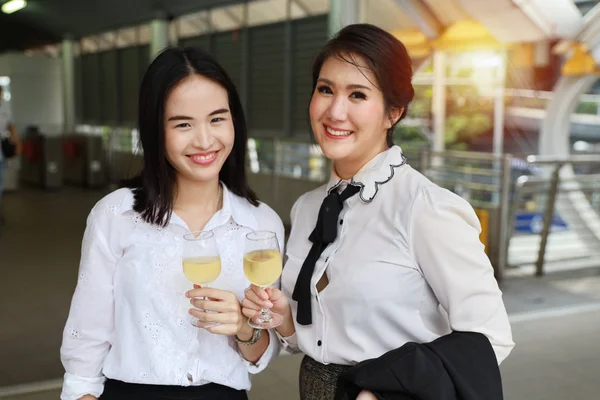 Erfolgreiche asiatische Geschäftsfrau hält lächelnd Sektgläser in der Hand, während sie draußen feiert — Stockfoto