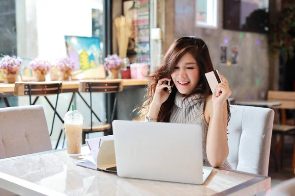 Piękna azjatycka kobieta w casual sukienka zakupy i płatności online na komputerze, pokazując kartę kredytową w restauracji z uśmiechniętym uśmiechem — Zdjęcie stockowe