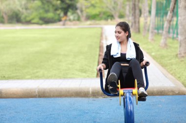 Mutlu gülümseyen, güzel Asyalı kadın spor giyim mağazasında egzersiz makinesinde dinleniyor. Güzel ve sportif bir kız yaz sabahı dışarıda bisikletle çalışıyor..