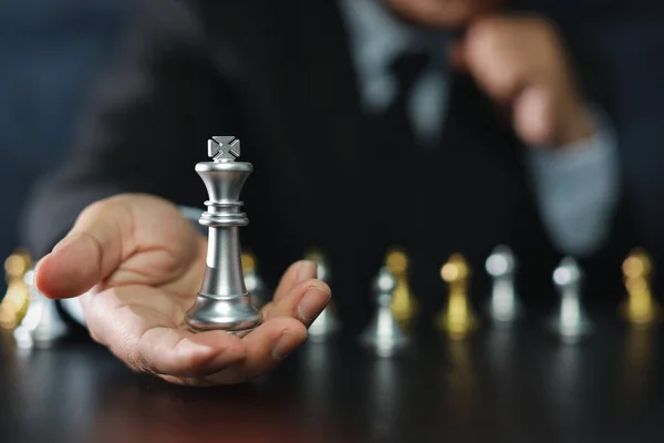 Businessman hands in black suite sitting and holding chess king on vintage table meaning of planning and strategy. Decision and achievement goal concept.