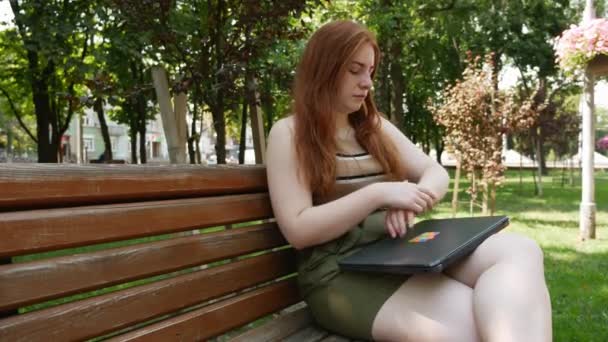 Menina Ruiva Trabalhando Atrás Laptop Parque Dia Ensolarado Banco — Vídeo de Stock