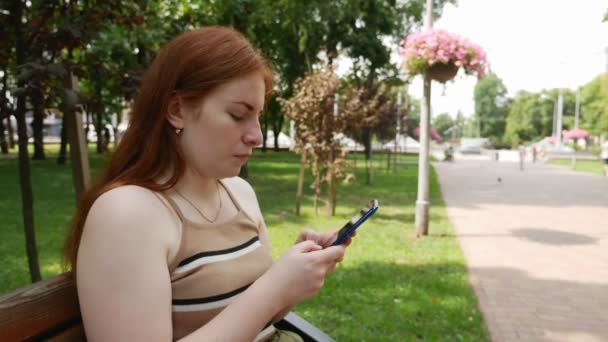 Redhead Meisje Het Park Communiceert Sociale Netwerken Zonnige Dag Bank — Stockvideo