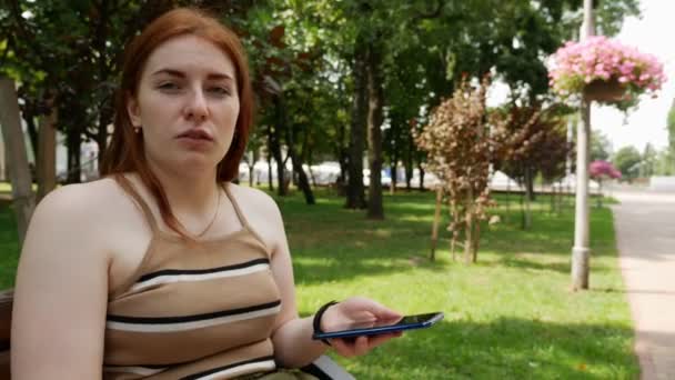 公园里的女孩在社交网络上交流 阳光明媚的日子在长椅上 — 图库视频影像