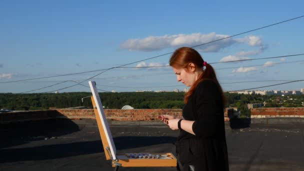 Red Haired Girl Paints Picture Roof House Sunny Day — Stock Video