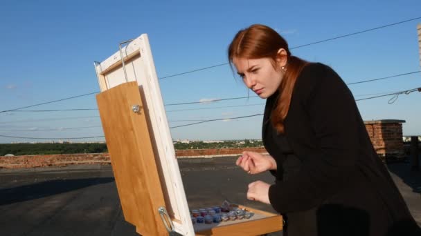赤毛の少女が絵を描く 晴れた日の家の屋根の上で — ストック動画