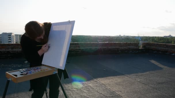 红头发的女孩画了一幅画 在阳光明媚的日子里 在房子的屋顶上 — 图库视频影像
