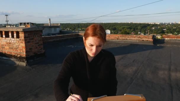 Red Haired Girl Paints Picture Roof House Sunny Day — Stock Video