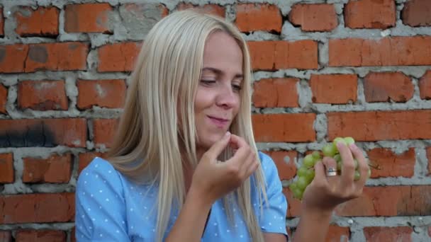 Mädchen Blauem Kleid Isst Trauben Backsteinhintergrund Glück Lächeln — Stockvideo