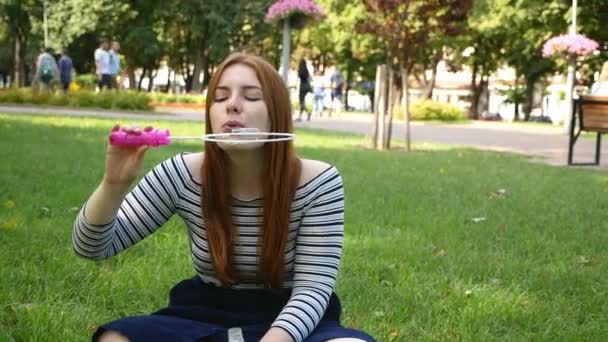 赤毛の女の子は公園で石鹸の泡を吹く 彼女は笑顔で笑う夏と幸せスローモーション — ストック動画