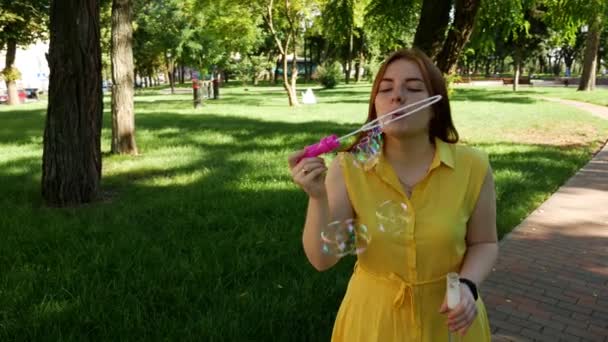 Рыжая Девушка Дует Мыльные Пузыри Парке Желтое Платье Улыбается Смеется — стоковое видео