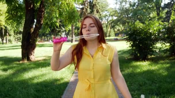 Roodharige Meisje Blaast Zeepbellen Het Park Gele Jurk Glimlachend Lachen — Stockvideo