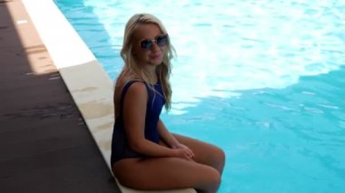 Mavi mayogiyen kız havuza bacaklarını sıçratıyor