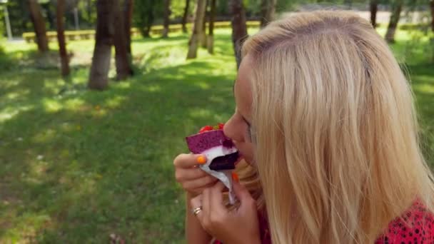 Ragazza Abito Rosso Mangia Torta Nel Parco — Video Stock