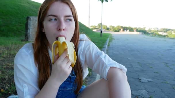 红发女孩在夏天在公园里吃水果 — 图库视频影像