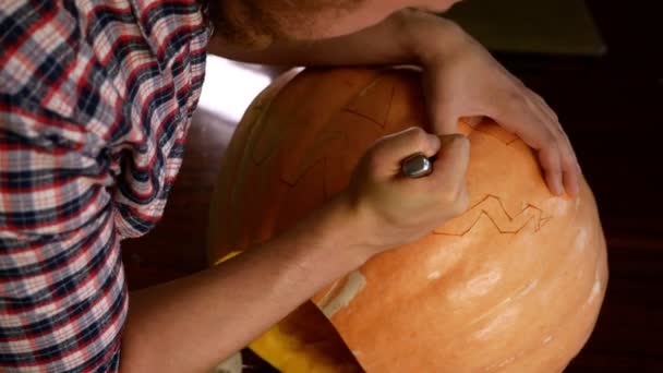 Een Man Carves Een Halloween Pompoen Een Mes Zijn Handen — Stockvideo