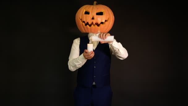 彫刻カボチャ かぼちゃの頭を持った男がろうそくに火をつけた ハロウィーンのコンセプト — ストック動画