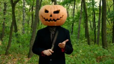 Sonbahar ormanında Halloween kabak baş yüzleri, elinde bir bıçak ile oynamak