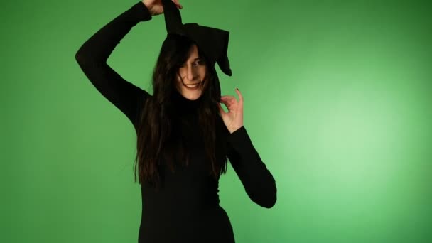 帽子の後ろに隠れている黒と魔女の帽子をかぶった若い美しい女性 ハロウィーン — ストック動画