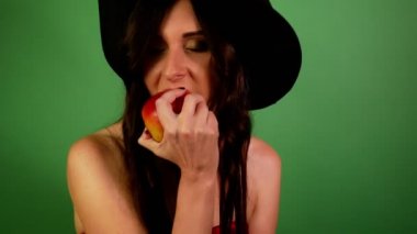 Yakın plan esmer kadın hevesle kırmızı elma yeşili yiyor..